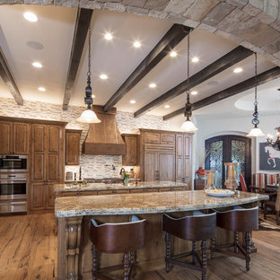 Inspiration for a large mediterranean l-shaped kitchen pantry in Austin with a double-bowl sink, raised-panel cabinets, light wood cabinets, granite benchtops, multi-coloured splashback, stone tile splashback, stainless steel appliances, light hardwood floors and multiple islands.