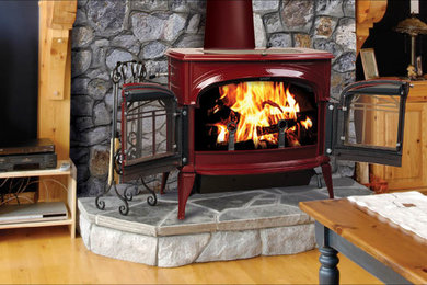 Example of a mid-sized arts and crafts light wood floor and brown floor family room design in Orange County with a wood stove, a metal fireplace, a tv stand and black walls