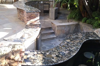 Patio kitchen - mid-sized tropical backyard stone patio kitchen idea in San Diego with a roof extension