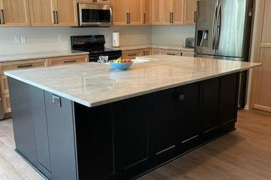 Large elegant l-shaped medium tone wood floor, brown floor and coffered ceiling eat-in kitchen photo in Portland with a farmhouse sink, shaker cabinets, light wood cabinets, quartzite countertops, stainless steel appliances, an island and gray countertops