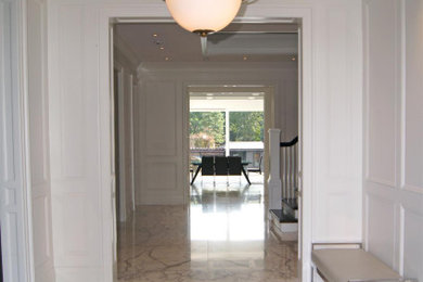 Large elegant marble floor, white floor, vaulted ceiling and wainscoting hallway photo in Toronto with white walls