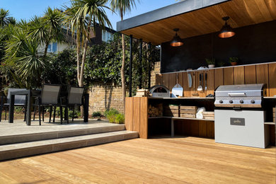 Design ideas for a mid-sized contemporary backyard partial sun garden for summer in London with decking.
