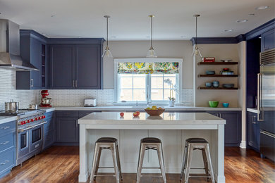 Example of a large transitional u-shaped medium tone wood floor and brown floor kitchen design in Chicago with a single-bowl sink, shaker cabinets, blue cabinets, quartzite countertops, white backsplash, ceramic backsplash, stainless steel appliances and an island