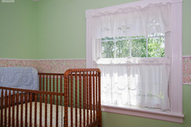 Diseño de habitación de bebé niña de tamaño medio con paredes verdes y suelo de madera oscura