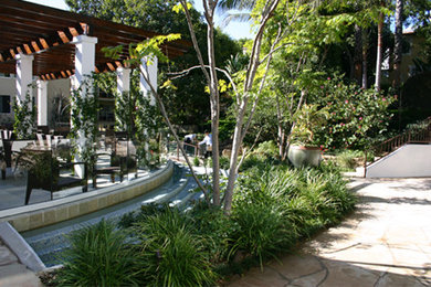 Photo of a large traditional partial sun backyard stone water fountain landscape in Los Angeles.