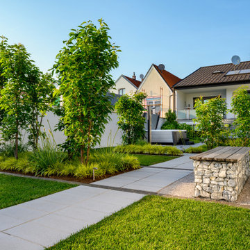 Klare Gartenwege mit Pflanzinseln und Gabionen-Sitzbank