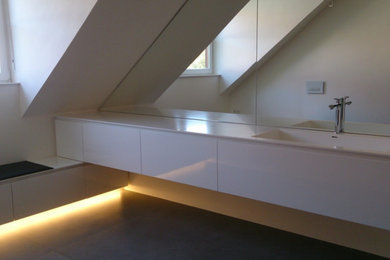 Großes Modernes Duschbad mit flächenbündigen Schrankfronten, weißen Schränken, bodengleicher Dusche, Wandtoilette, weißer Wandfarbe, Keramikboden, integriertem Waschbecken, Mineralwerkstoff-Waschtisch, grauem Boden und offener Dusche in Sonstige