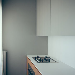 Small modern kitchen pantry inspiration - Example of a small minimalist single-wall ceramic floor kitchen pantry design in Milan with flat-panel cabinets, light wood cabinets, solid surface countertops, white backsplash, stainless steel appliances and an undermount sink