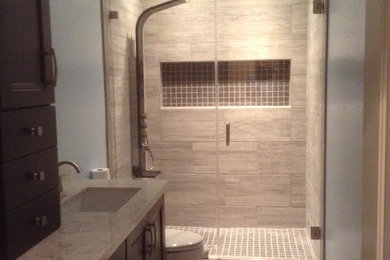 Alcove shower - mid-sized transitional master gray tile and porcelain tile porcelain tile and gray floor alcove shower idea in Los Angeles with shaker cabinets, dark wood cabinets, a two-piece toilet, blue walls, an undermount sink, quartzite countertops, a hinged shower door and white countertops