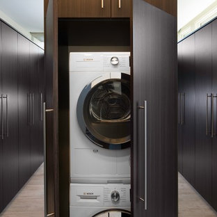 Design ideas for an expansive contemporary u-shaped utility room in Sacramento with flat-panel cabinets, dark wood cabinets, beige walls, porcelain flooring and a stacked washer and dryer.