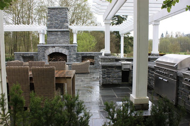 This is an example of a mid-sized traditional courtyard patio in Seattle with an outdoor kitchen, natural stone pavers and a pergola.