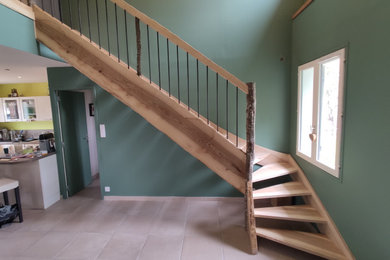 This is an example of a medium sized country wood l-shaped metal railing staircase in Lyon with open risers.