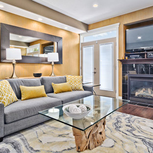 Inredning av ett modernt mellanstort separat vardagsrum, med gula väggar, mellanmörkt trägolv, en standard öppen spis, en spiselkrans i sten och en fristående TV