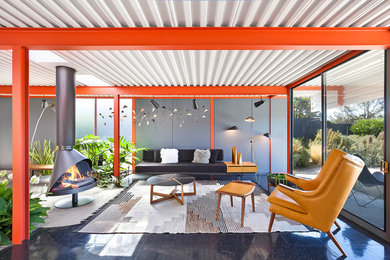Example of a 1960s black floor living room design in San Francisco with gray walls and a hanging fireplace