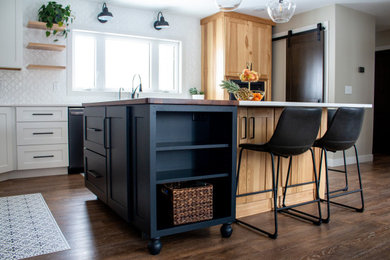 Foto de cocina comedor moderna con fregadero bajoencimera, salpicadero blanco, electrodomésticos negros, suelo laminado, una isla, suelo marrón y encimeras blancas