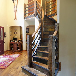 Large rustic wood curved wood railing staircase in Denver with slate risers.