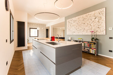 Photo of a large contemporary single-wall open plan kitchen in Catania-Palermo with an undermount sink, glass-front cabinets, grey cabinets, quartz benchtops, black appliances, cement tiles, with island, multi-coloured floor and white benchtop.