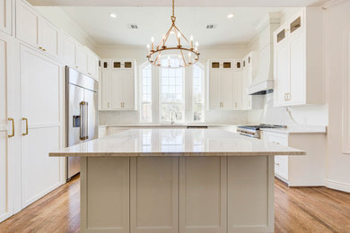Example of a huge transitional galley medium tone wood floor, brown floor and vaulted ceiling eat-in kitchen design in Houston with an undermount sink, shaker cabinets, white cabinets, quartzite countertops, white backsplash, mosaic tile backsplash, stainless steel appliances, an island and white countertops