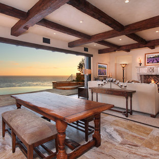 На фото: большие гостиные-столовые в средиземноморском стиле с бежевыми стенами, полом из известняка, стандартным камином и фасадом камина из камня