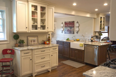 Mid-sized country eat-in kitchen in Cincinnati with a farmhouse sink, flat-panel cabinets, white cabinets, granite benchtops, white splashback, porcelain splashback, stainless steel appliances, dark hardwood floors and with island.