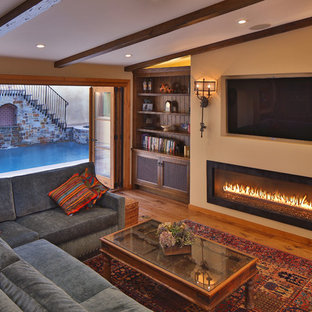 Mediterranes Wohnzimmer mit braunem Holzboden, Gaskamin und Wand-TV in Los Angeles