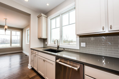 Large transitional l-shaped medium tone wood floor and multicolored floor eat-in kitchen photo in Grand Rapids with an undermount sink, shaker cabinets, dark wood cabinets, quartz countertops, green backsplash, glass tile backsplash, stainless steel appliances, an island and beige countertops