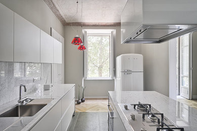 This is an example of a mediterranean u-shaped kitchen in Amsterdam with white cabinets, with island, an undermount sink, marble benchtops, stone slab splashback and white appliances.