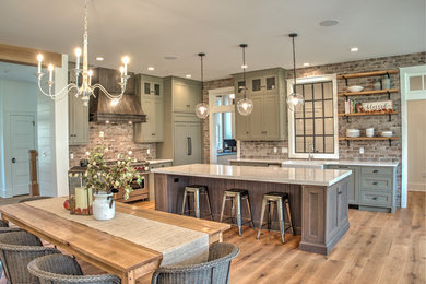 Design ideas for a mid-sized transitional l-shaped open plan kitchen in Philadelphia with a farmhouse sink, shaker cabinets, brick splashback, stainless steel appliances, with island, white benchtop, grey cabinets, quartz benchtops, red splashback, light hardwood floors and beige floor.
