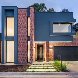 Inspiration för ett funkis rött hus, med två våningar, tegel, platt tak och tak i metall