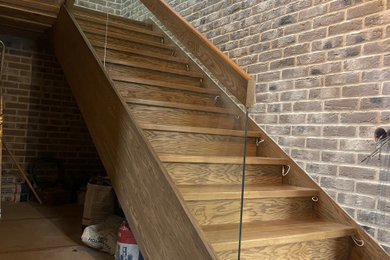 Свежая идея для дизайна: п-образная деревянная лестница среднего размера в стиле модернизм с деревянными ступенями и стеклянными перилами - отличное фото интерьера