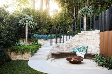 Inspiration for a tropical backyard patio in Sydney with a fire feature, natural stone pavers and no cover.