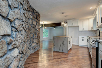 Inspiration for a mid-sized contemporary l-shaped medium tone wood floor and brown floor eat-in kitchen remodel in Other with an undermount sink, recessed-panel cabinets, white cabinets, granite countertops, white backsplash, porcelain backsplash, stainless steel appliances, an island and beige countertops