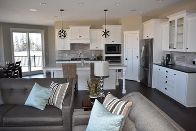 Example of a mid-sized transitional l-shaped dark wood floor and brown floor open concept kitchen design in Minneapolis with shaker cabinets, white cabinets, an island, a double-bowl sink, quartz countertops, multicolored backsplash, stone tile backsplash and stainless steel appliances
