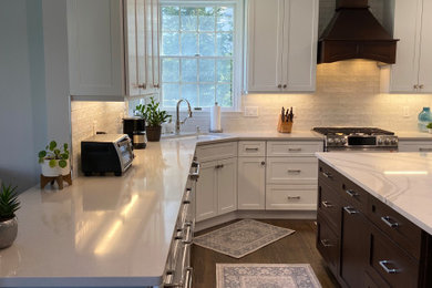 Example of a mid-sized transitional u-shaped brown floor and dark wood floor eat-in kitchen design in New York with an undermount sink, shaker cabinets, white cabinets, quartz countertops, white backsplash, ceramic backsplash, stainless steel appliances, an island and white countertops
