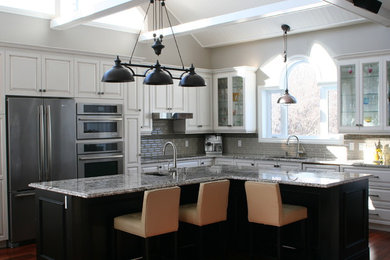 Open concept kitchen - large traditional l-shaped dark wood floor open concept kitchen idea in Montreal with an undermount sink, raised-panel cabinets, white cabinets, granite countertops, beige backsplash, matchstick tile backsplash, stainless steel appliances and an island
