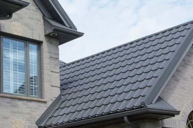 Inspiration for a large gray two-story brick exterior home remodel in Ottawa with a tile roof and a black roof