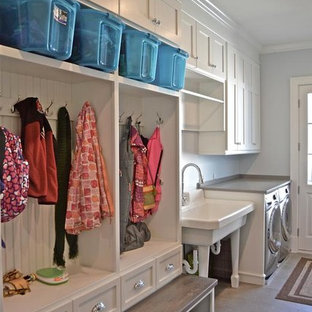 Medium sized traditional single-wall utility room in Chicago with an utility sink, shaker cabinets, white cabinets, composite countertops, grey walls, limestone flooring and a side by side washer and dryer.