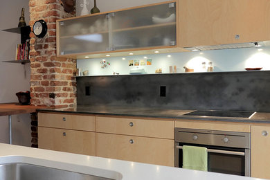 Small eclectic galley kitchen photo in Montreal with an undermount sink, flat-panel cabinets, concrete countertops, gray backsplash, stainless steel appliances and an island