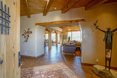 Entryway - large southwestern brick floor and exposed beam entryway idea in Albuquerque with beige walls and a medium wood front door