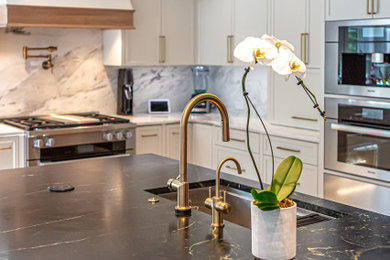 Example of a huge minimalist l-shaped light wood floor open concept kitchen design in Richmond with a drop-in sink, white cabinets, granite countertops, multicolored backsplash, granite backsplash, stainless steel appliances, an island and white countertops