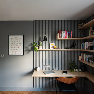 Bild på ett mellanstort minimalistiskt hemmabibliotek, med grå väggar, korkgolv, ett inbyggt skrivbord och brunt golv