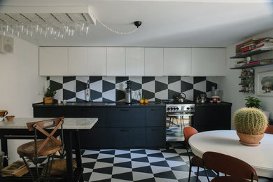Mid-sized eclectic single-wall open plan kitchen in Naples with a single-bowl sink, flat-panel cabinets, black cabinets, laminate benchtops, porcelain splashback, stainless steel appliances, porcelain floors, black floor and black benchtop.