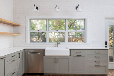 Inspiration for a large transitional u-shaped medium tone wood floor, vaulted ceiling and brown floor eat-in kitchen remodel in Austin with a farmhouse sink, shaker cabinets, green cabinets, quartzite countertops, white backsplash, stainless steel appliances, no island, white countertops and ceramic backsplash