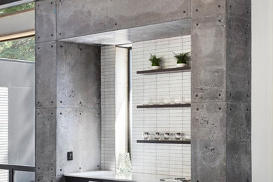 Industrial single-wall home bar in Other with flat-panel cabinets, black cabinets, white splashback, concrete floors and grey floor.