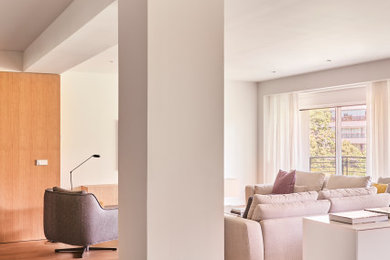 Modelo de salón abierto de obra con paredes beige y suelo de madera en tonos medios