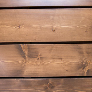 Ejemplo de sótano con puerta rústico, grande, con paredes marrones, suelo de madera clara, chimenea tradicional y marco de chimenea de piedra