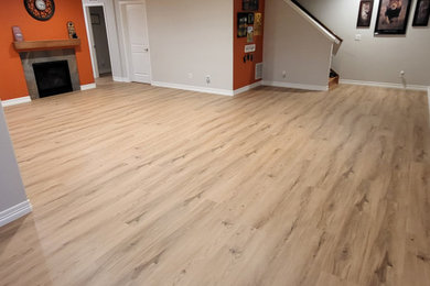 Example of a large classic walk-out laminate floor and brown floor basement design in Denver with multicolored walls, a standard fireplace and a tile fireplace