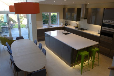 Mid-sized contemporary l-shaped open plan kitchen with an undermount sink, flat-panel cabinets, grey cabinets, quartzite benchtops, white splashback, glass sheet splashback, stainless steel appliances, porcelain floors and with island.