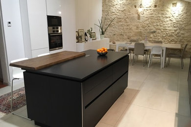 Photo of a large contemporary galley open plan kitchen in Bordeaux with an integrated sink, flat-panel cabinets, black cabinets, granite benchtops, white splashback, ceramic splashback, stainless steel appliances, ceramic floors and with island.