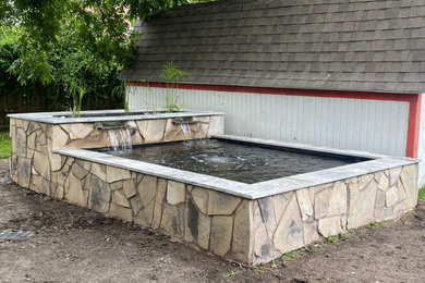 Modelo de piscina con fuente elevada clásica de tamaño medio rectangular en patio trasero con adoquines de piedra natural